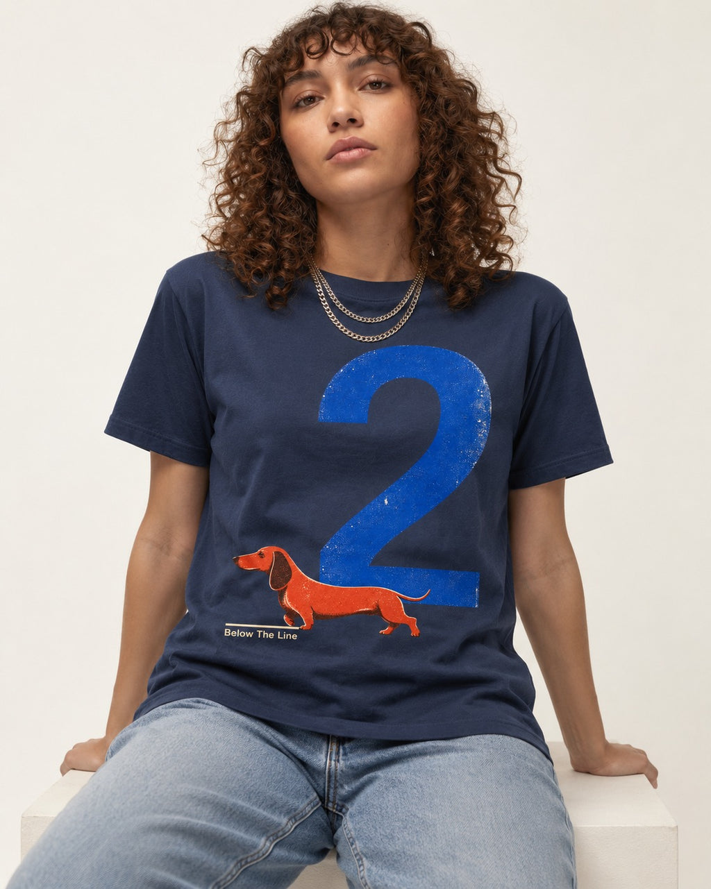 Dachshund Below The Line Number Two Graphic T-Shirt in Navy, worn by a seated model