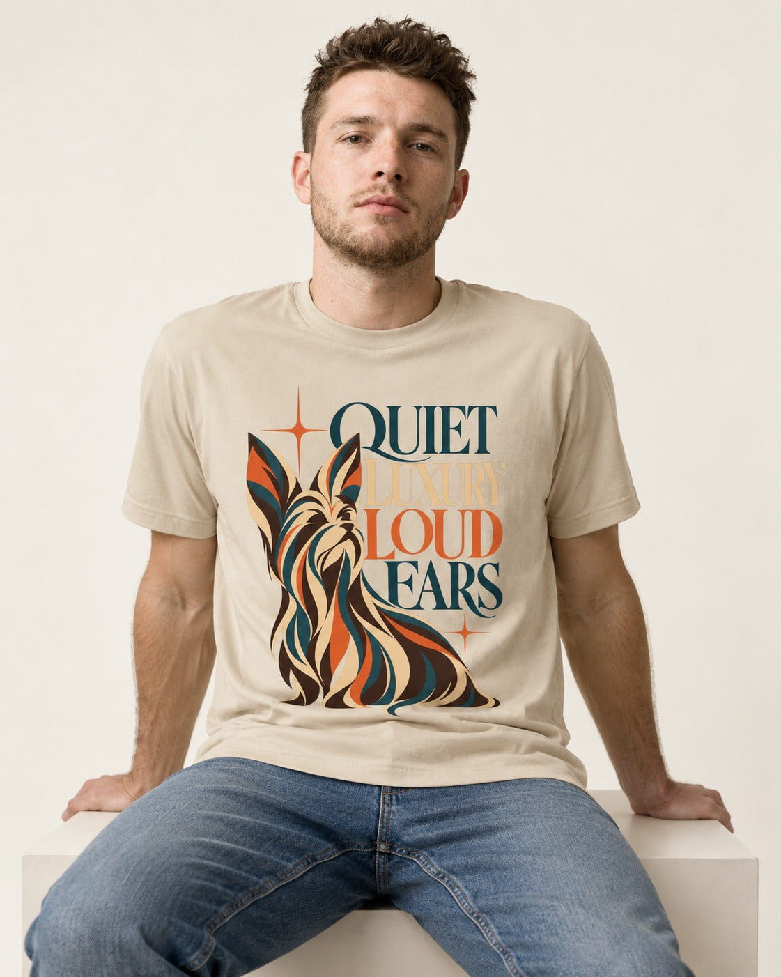 Quiet Luxury Loud Ears Yorkshire Terrier T-Shirt in Sand, worn by a seated model