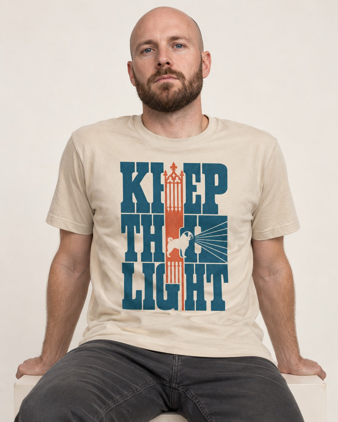 Keep the Pug Fight T-Shirt in Sand, worn by a seated model