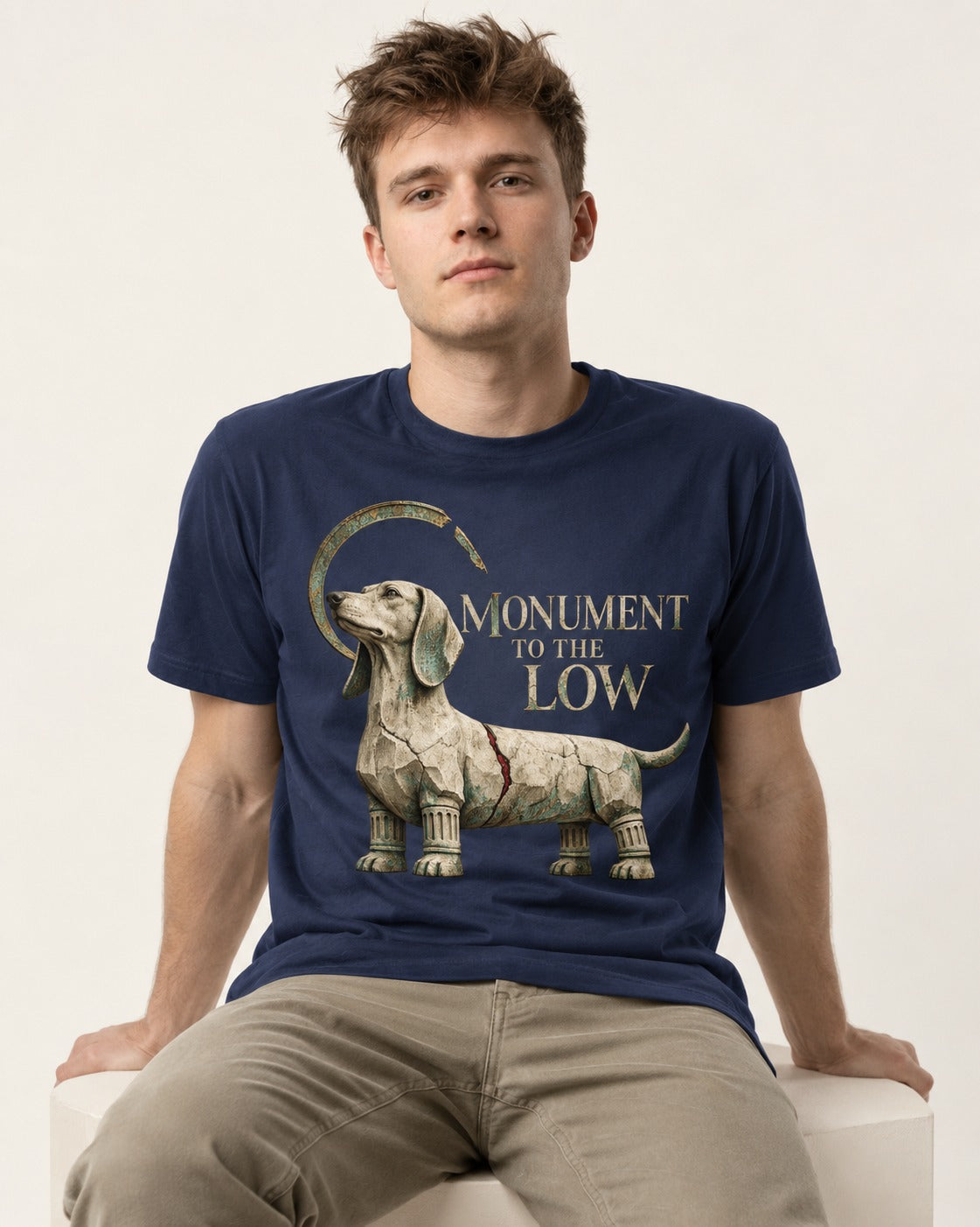 Dachshund Monument to the Low Stone Statue Graphic T-Shirt in Navy, worn by a seated model