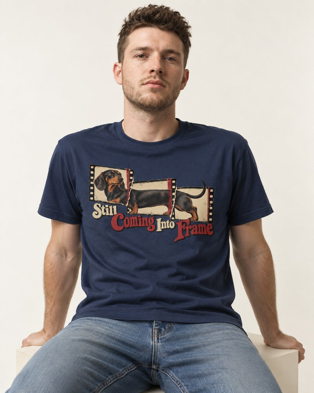 Dachshund Still Coming Into Frame Vintage Filmstrip Graphic T-Shirt in Navy, worn by a seated model