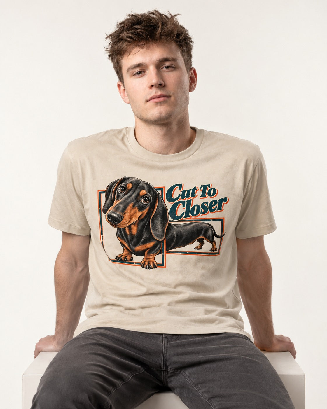 Dachshund Cut to Closer T-Shirt in Sand, worn by a seated model
