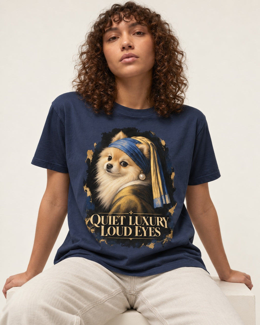 Pomeranian Quiet Luxury Loud Eyes Pearl Portrait Graphic T-Shirt in Navy, worn by a seated model