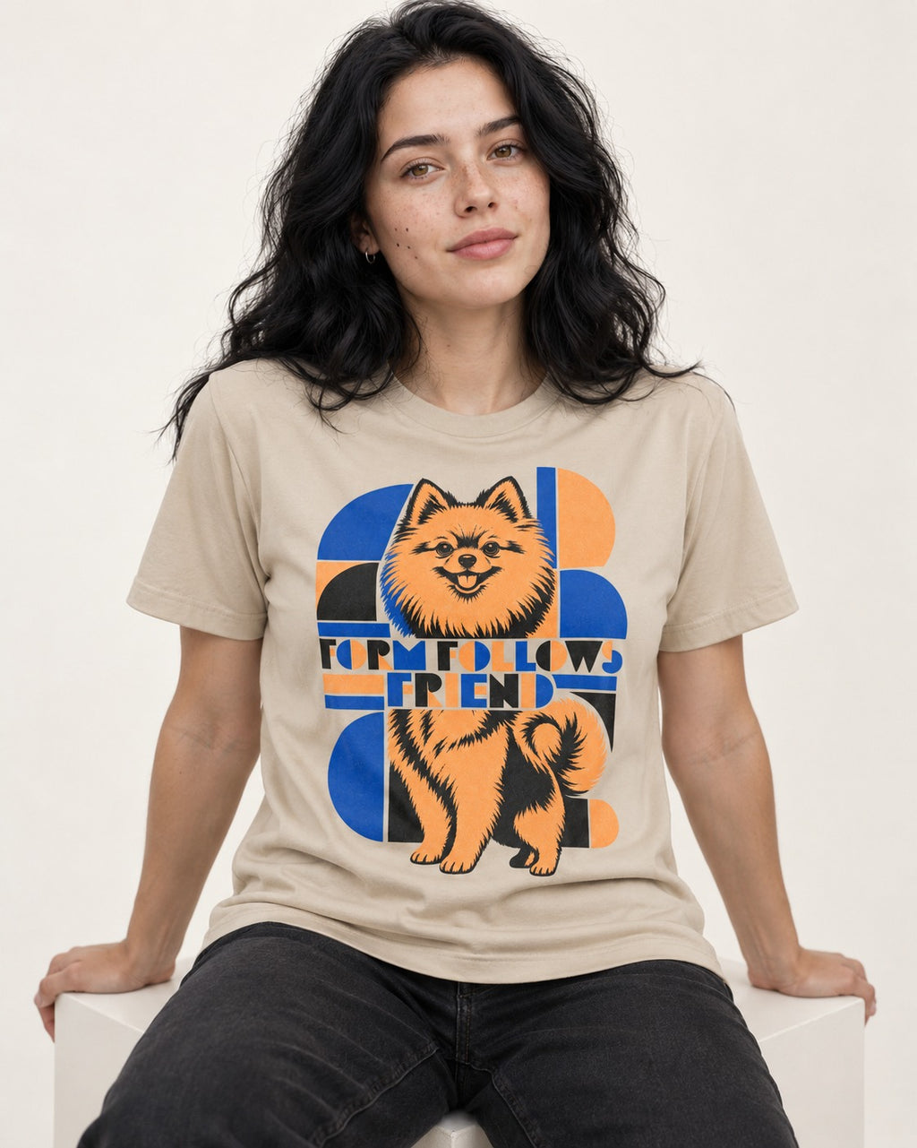Form Follows Pomeranian Friend T-Shirt in Sand, worn by a seated model