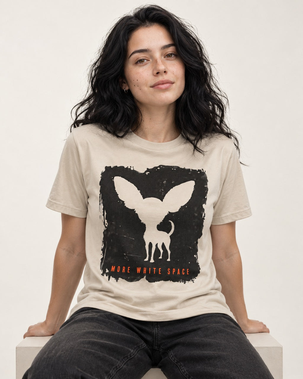More White Space Chihuahua T-Shirt in Sand, worn by a seated model