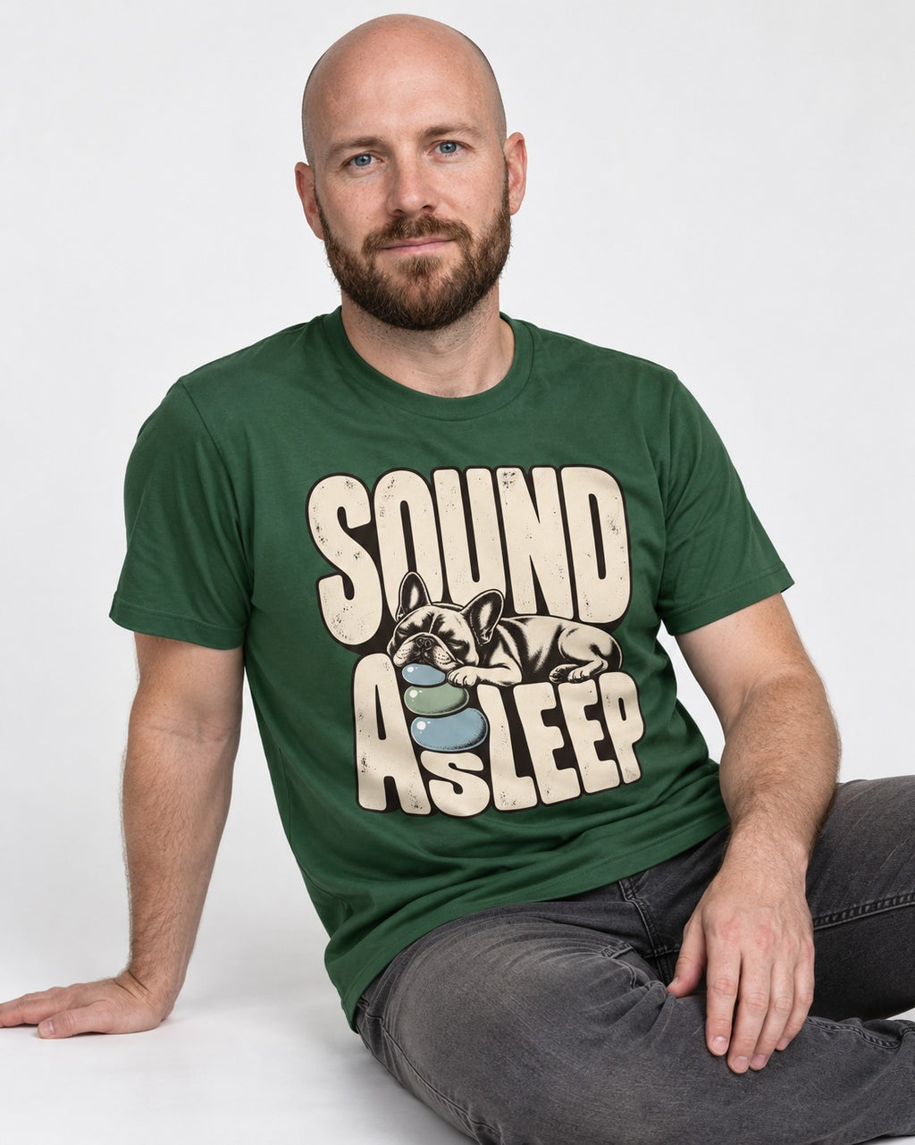 Frenchie Sound Asleep Stone Pillow Graphic T-Shirt in Forest Green, worn by a seated model
