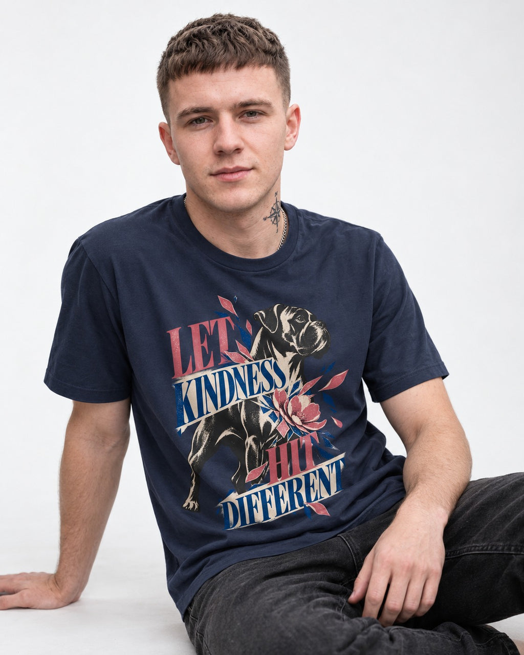 Let Kindness Hit Different Boxer Floral Collage T-Shirt in Navy, worn by a seated model