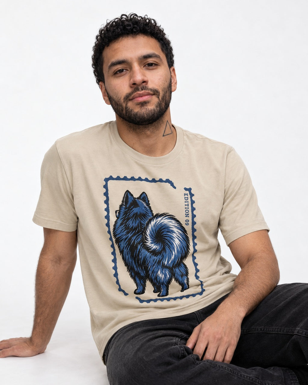 Pomeranian Pride T-Shirt in Sand, worn by a seated model