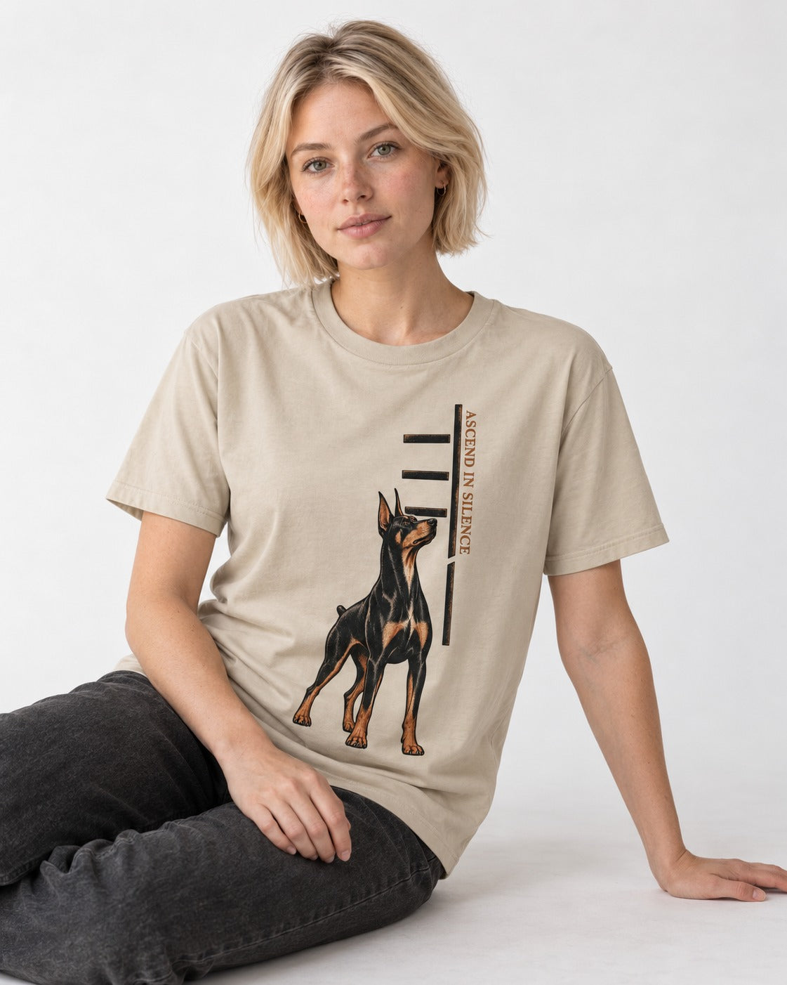 Doberman Ascend in Silence T-Shirt in Sand, worn by a seated model
