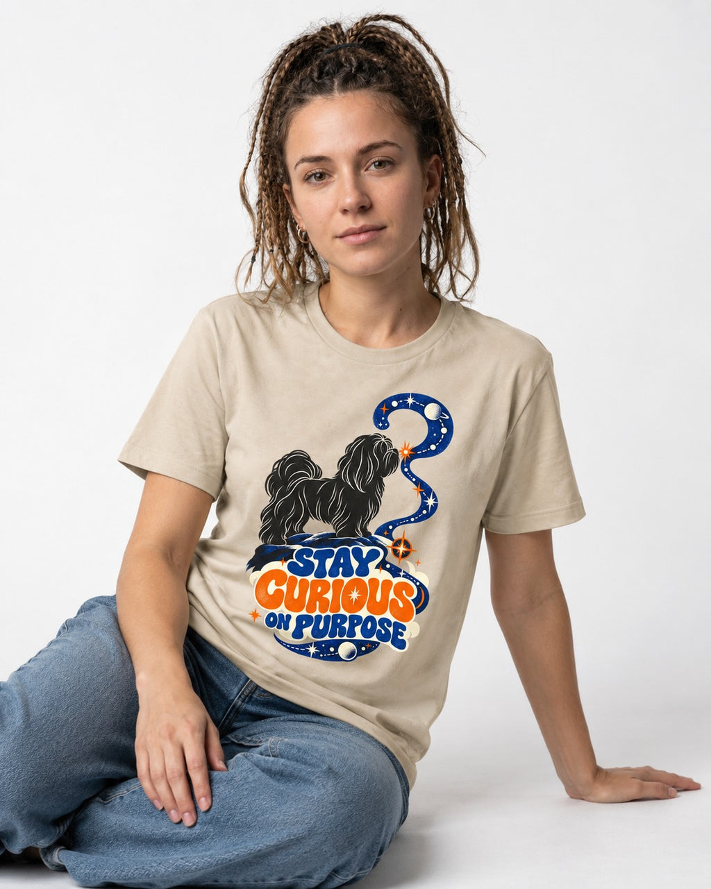 Stay Curious on Purpose Shih Tzu T-Shirt in Sand, worn by a seated model