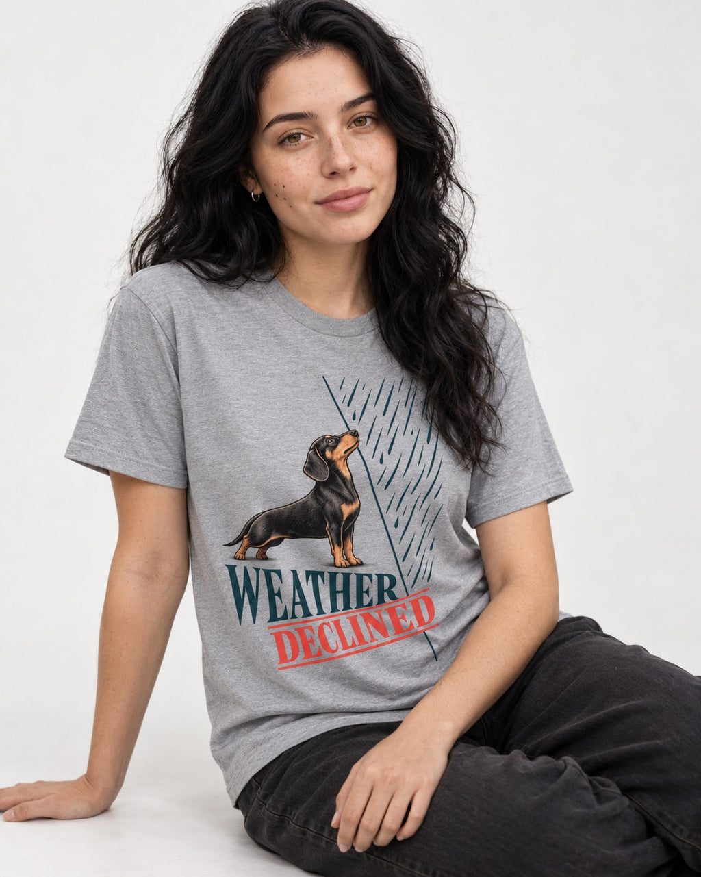 Weather Declined by Dachshund T-Shirt in Sport Grey, worn by a seated model