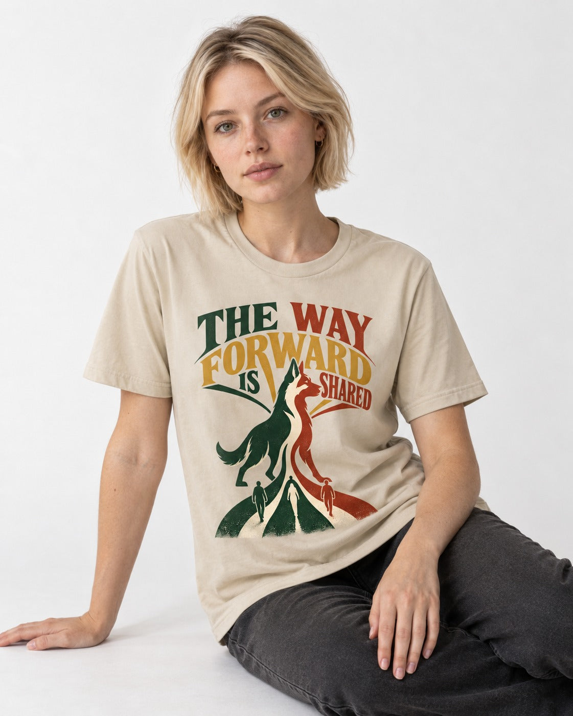 Shared Way Forward German Shepherd Dog T-Shirt in Sand, worn by a seated model