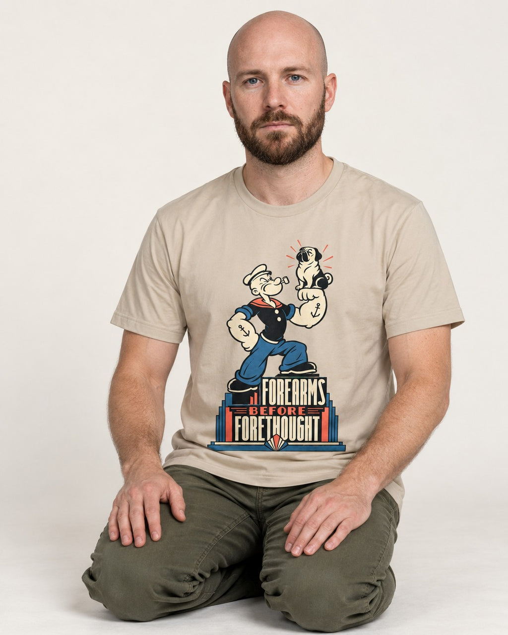 Pug Forearms Before Forethought T-Shirt in Sand, worn by a seated model
