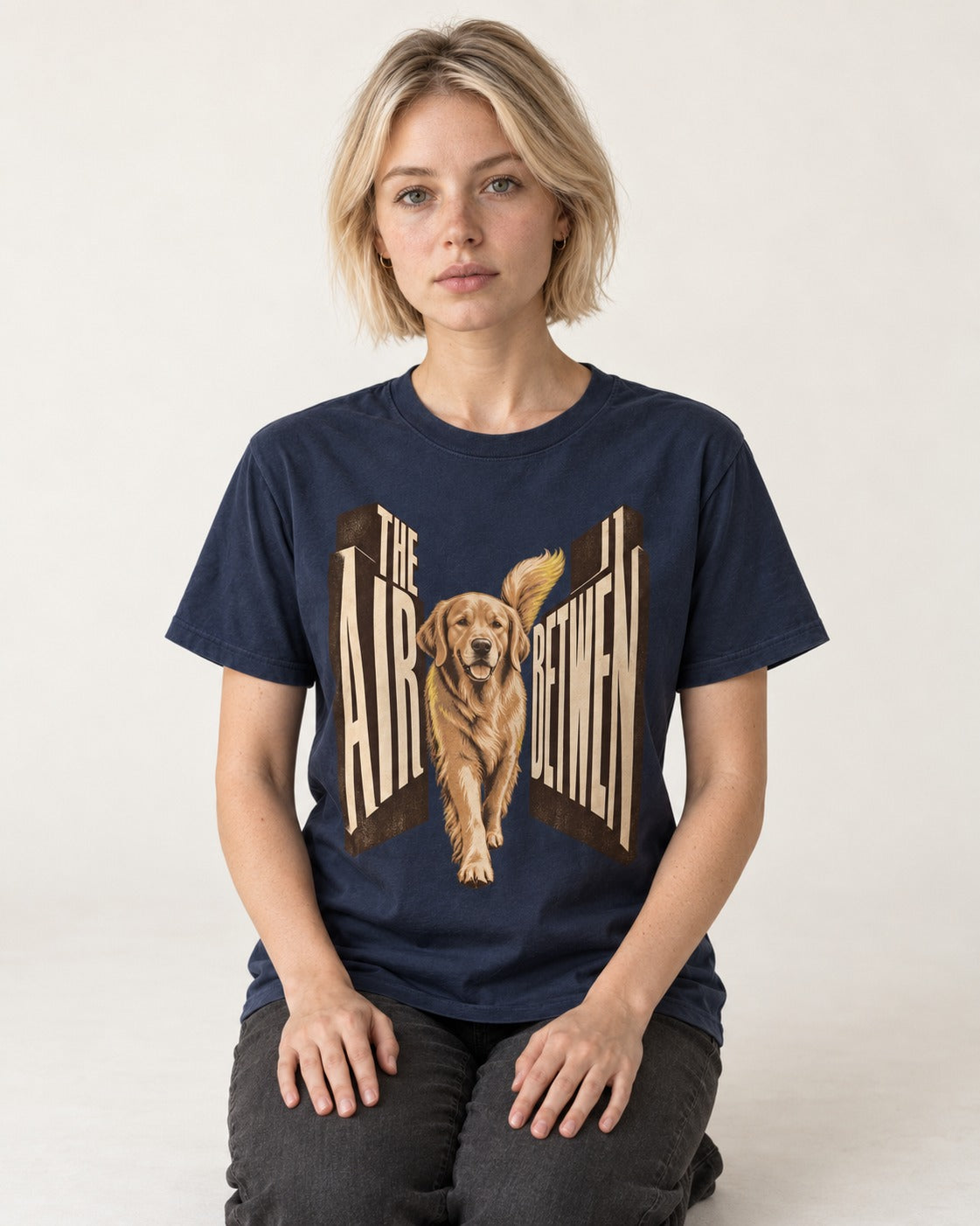 The Air Between Dimensional Golden Retriever Graphic T-Shirt in Navy, worn by a seated model