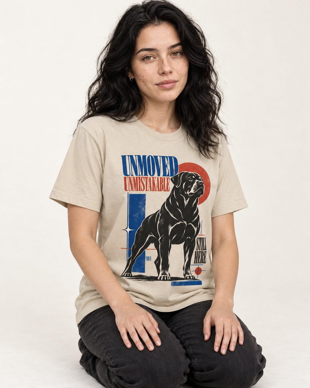 Unmoved Unmistakable Rottweiler T-Shirt in Sand, worn by a seated model
