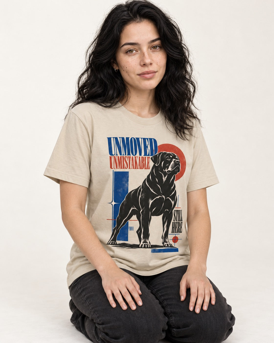 Unmoved Unmistakable Rottweiler T-Shirt in Sand, worn by a seated model