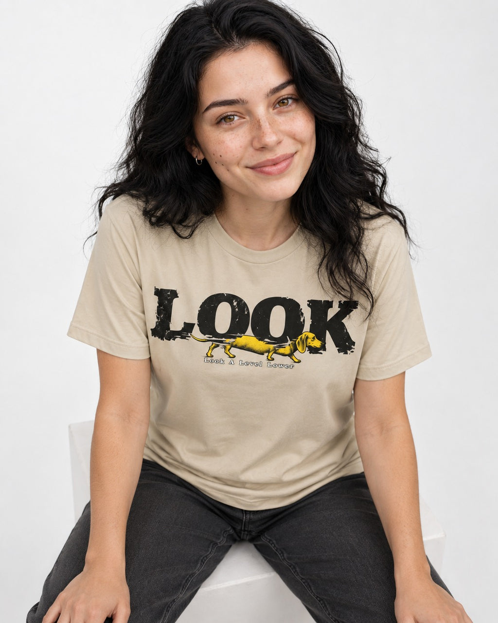 Look Lower for Dachshund T-Shirt in Sand, worn by a seated model