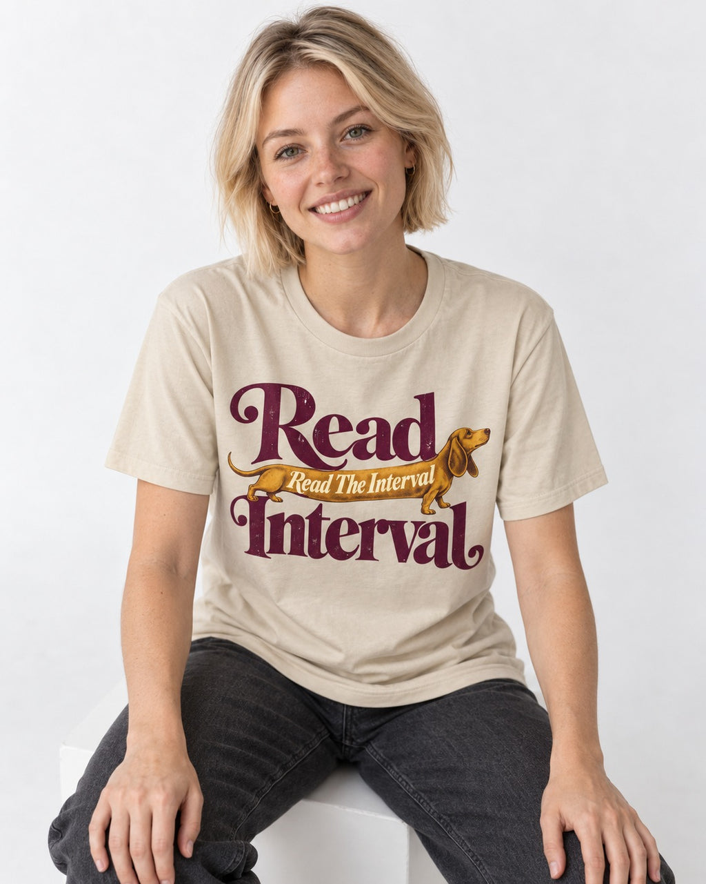 Read the Dachshund Interval T-Shirt in Sand, worn by a seated model