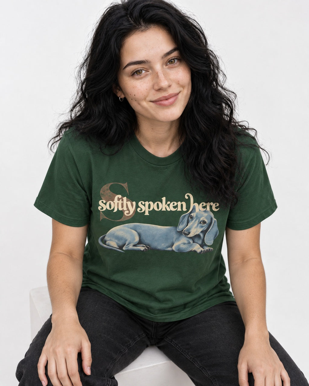 Dachshund Softly Spoken Here Reclining Portrait Graphic T-Shirt in Forest Green, worn by a seated model