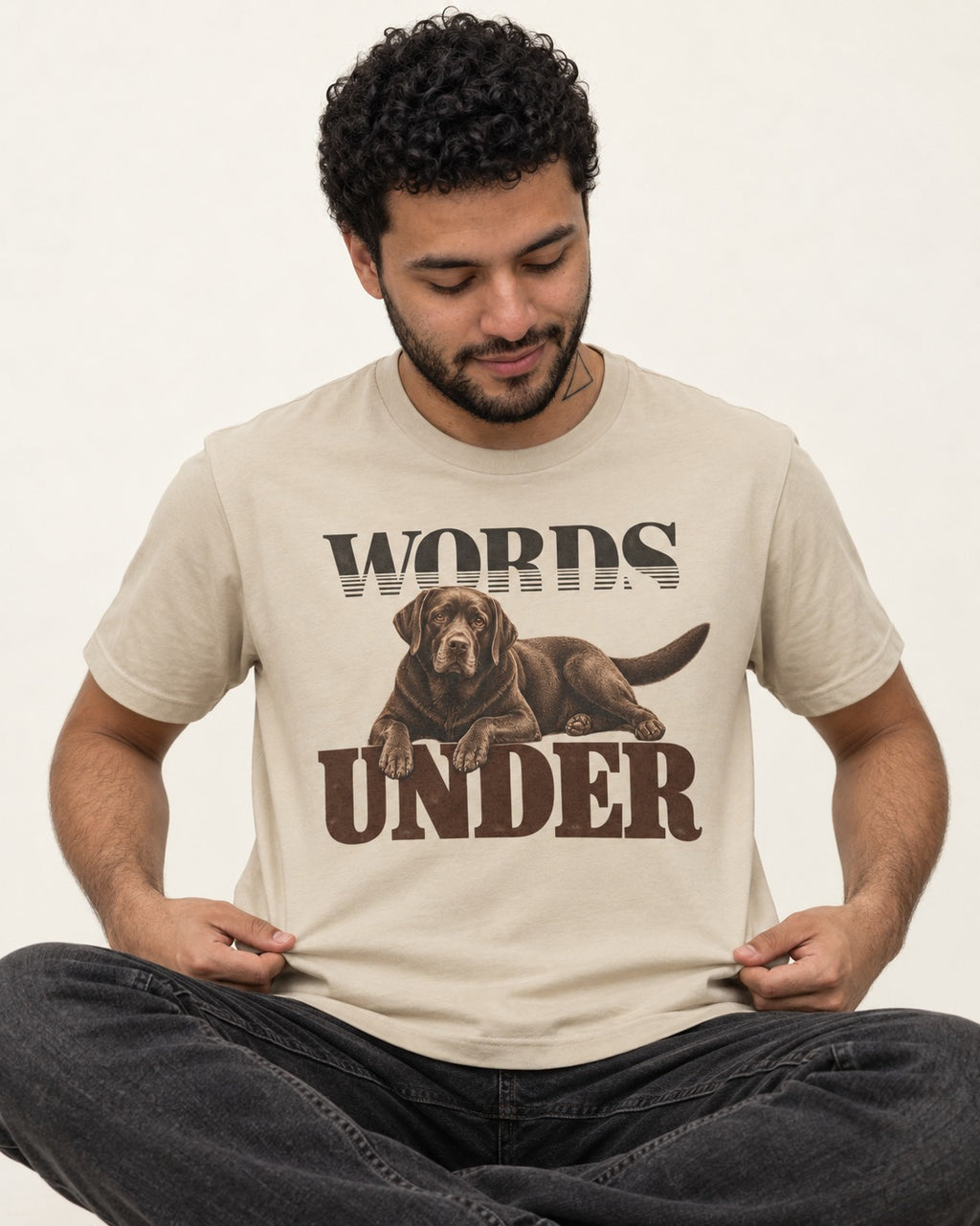 Words Under Labrador Retriever T-Shirt in Sand, worn by a seated model