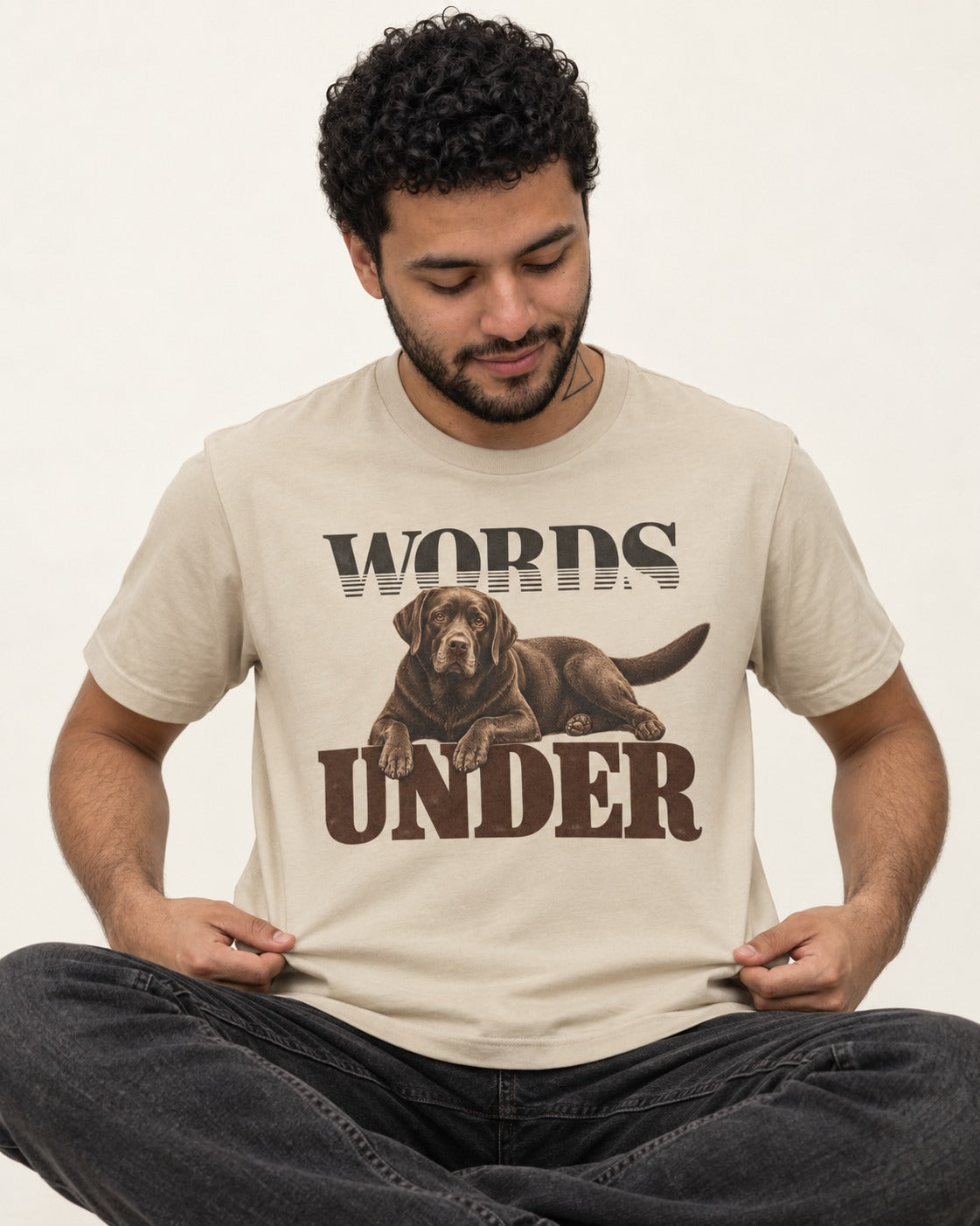 Words Under Labrador Retriever T-Shirt in Sand, worn by a seated model