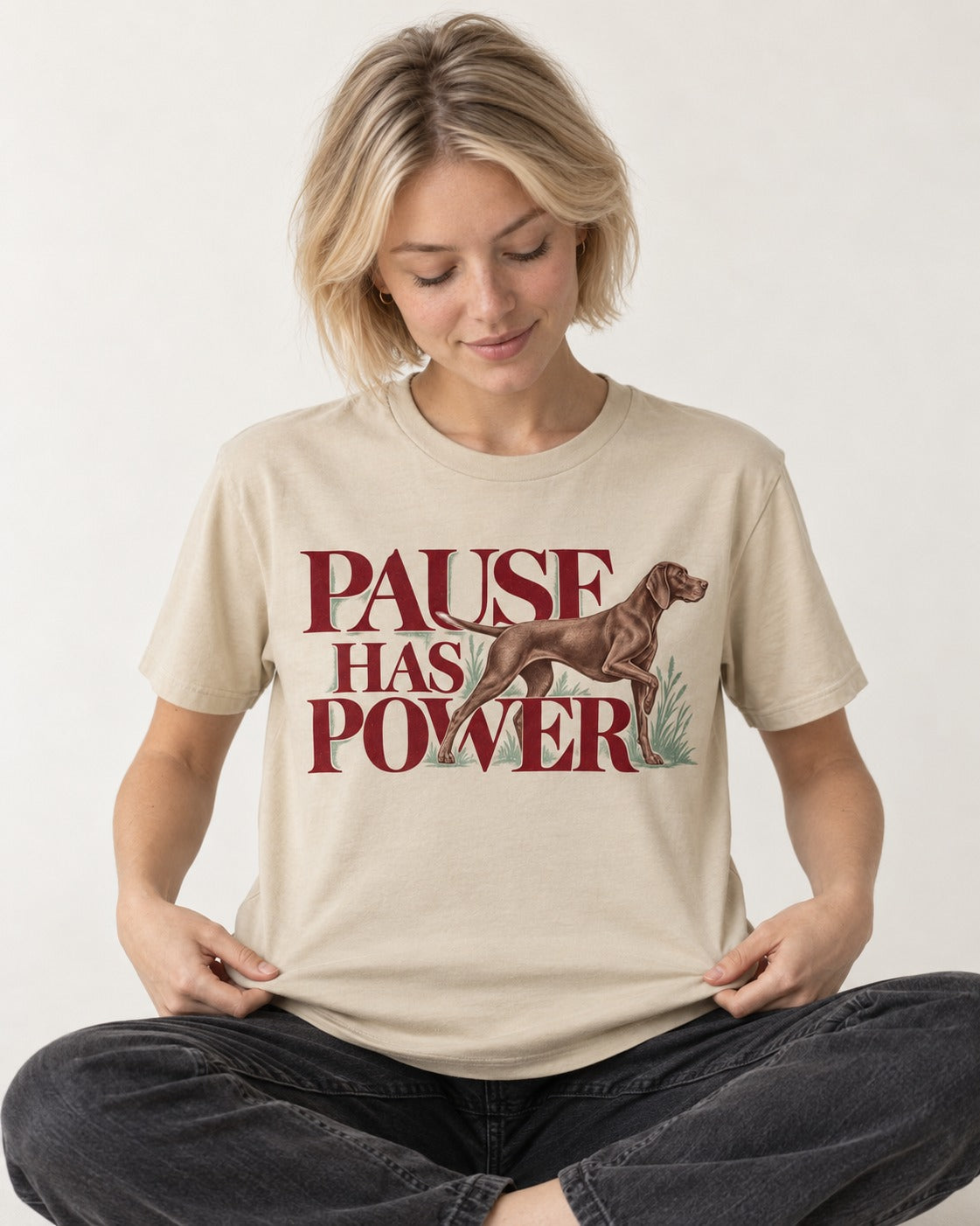 Pause Has Power German Shorthaired Pointer T-Shirt in Sand, worn by a seated model
