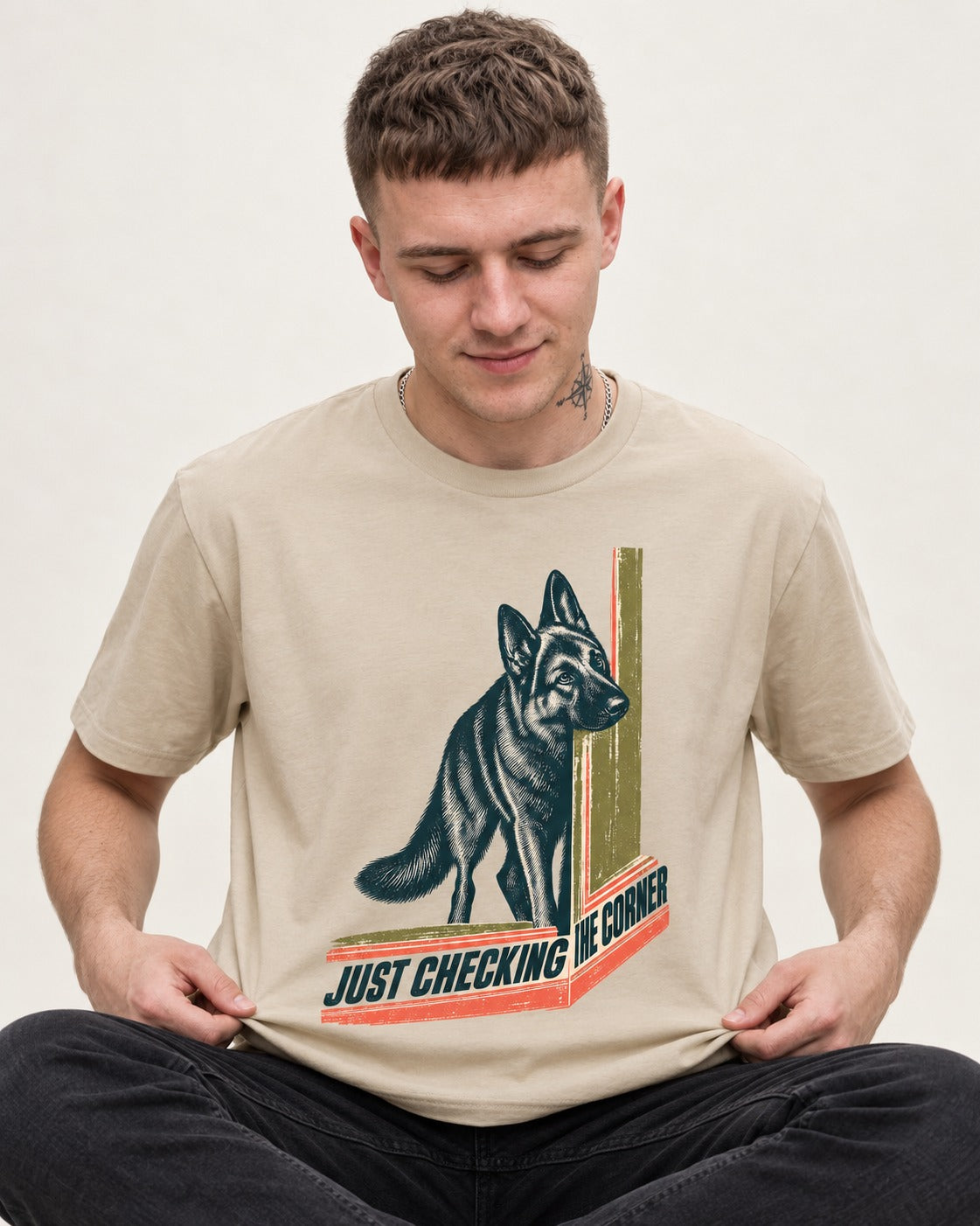 German Shepherd Dog Just Checking the Corner T-Shirt in Sand, worn by a seated model