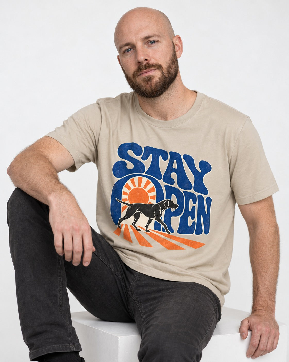 Stay Open German Shorthaired Pointer T-Shirt in Sand, worn by a seated model