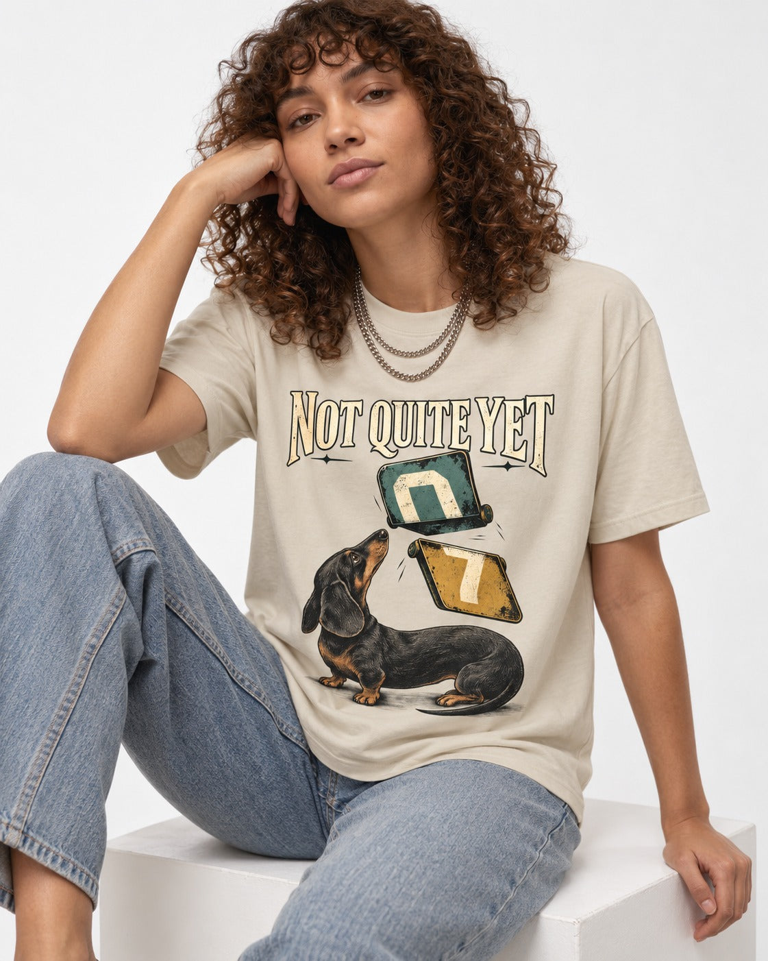 Not Quite Yet Dachshund T-Shirt in Sand, worn by a seated model