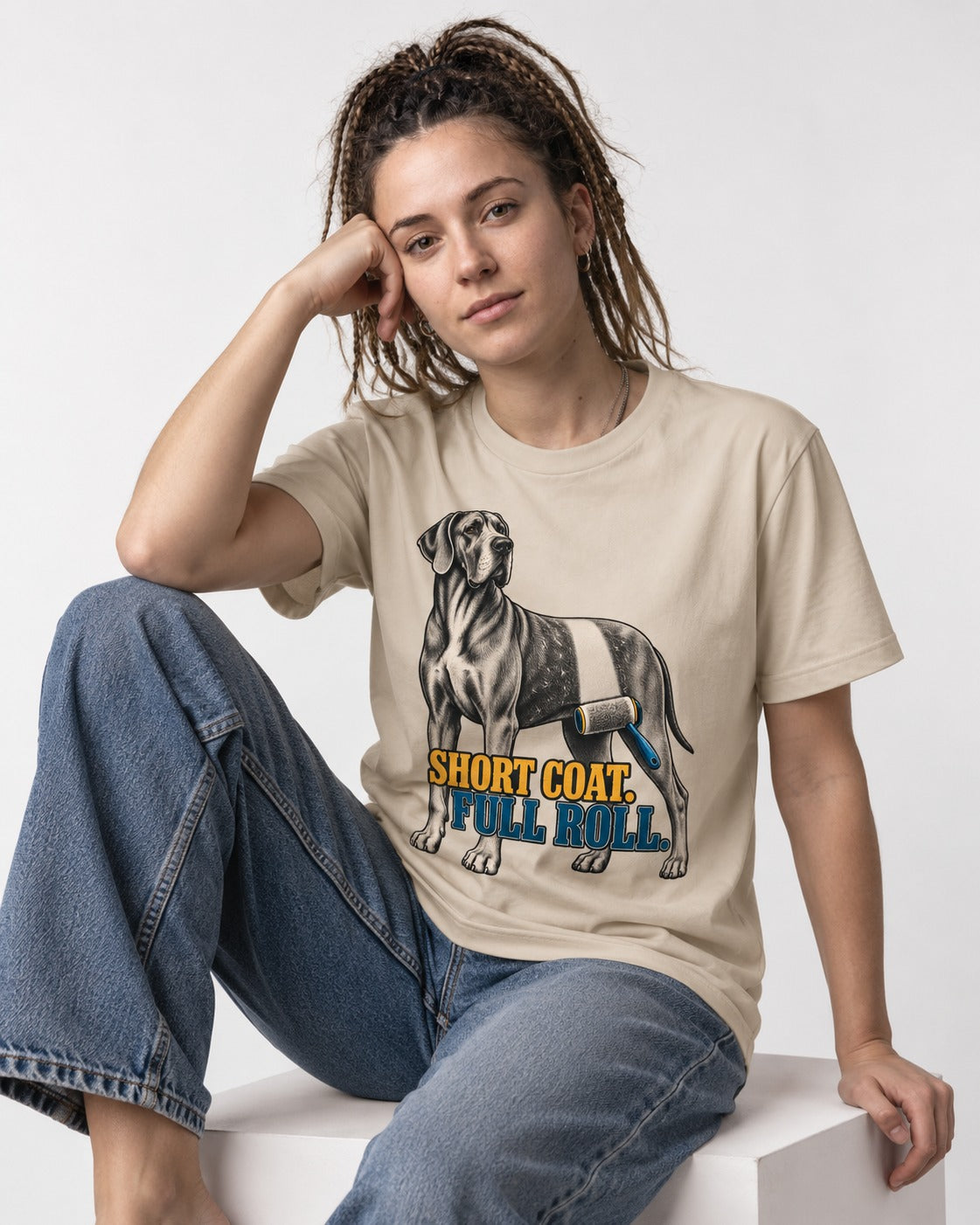 Short Coat Full Roll Great Dane T-Shirt in Sand, worn by a seated model