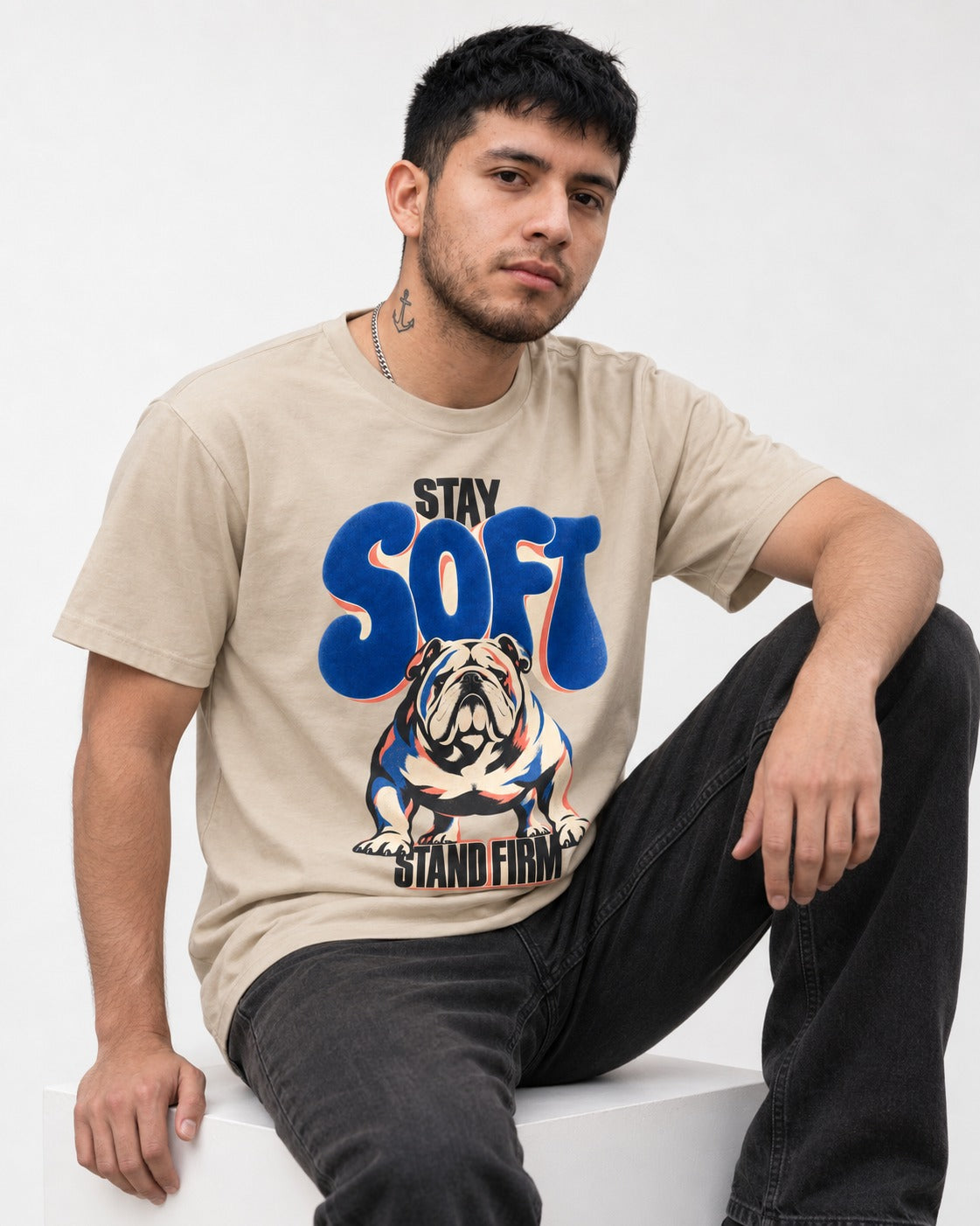 Stay Soft Stand Firm English Bulldog T-Shirt in Sand, worn by a seated model
