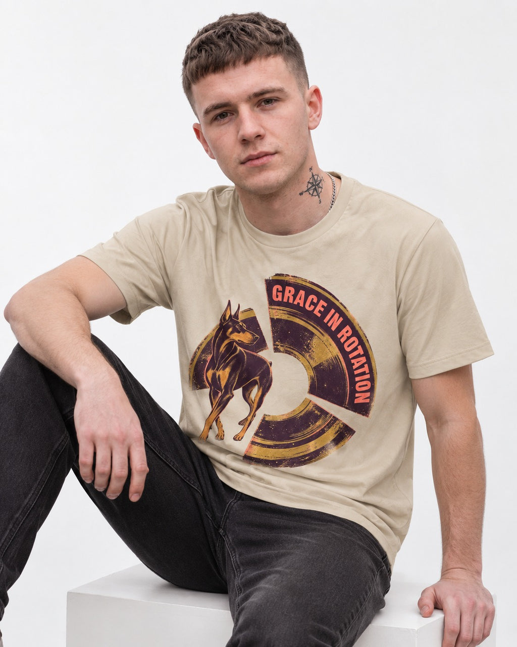 Doberman Grace in Rotation T-Shirt in Sand, worn by a seated model