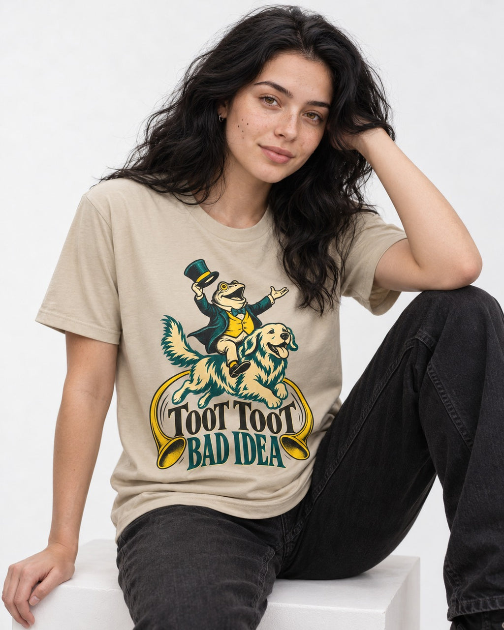 Golden Retriever Toot Toot Bad Idea T-Shirt in Sand, worn by a seated model