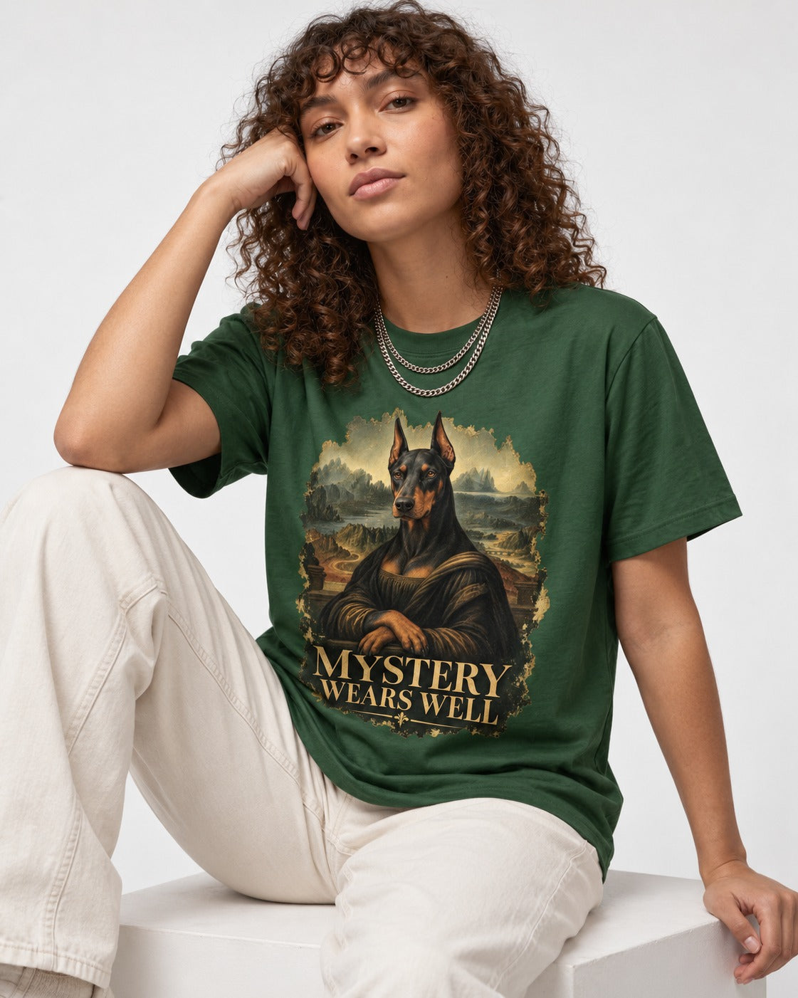 Doberman Mystery Wears Well Renaissance Portrait Graphic T-Shirt in Forest Green, worn by a seated model