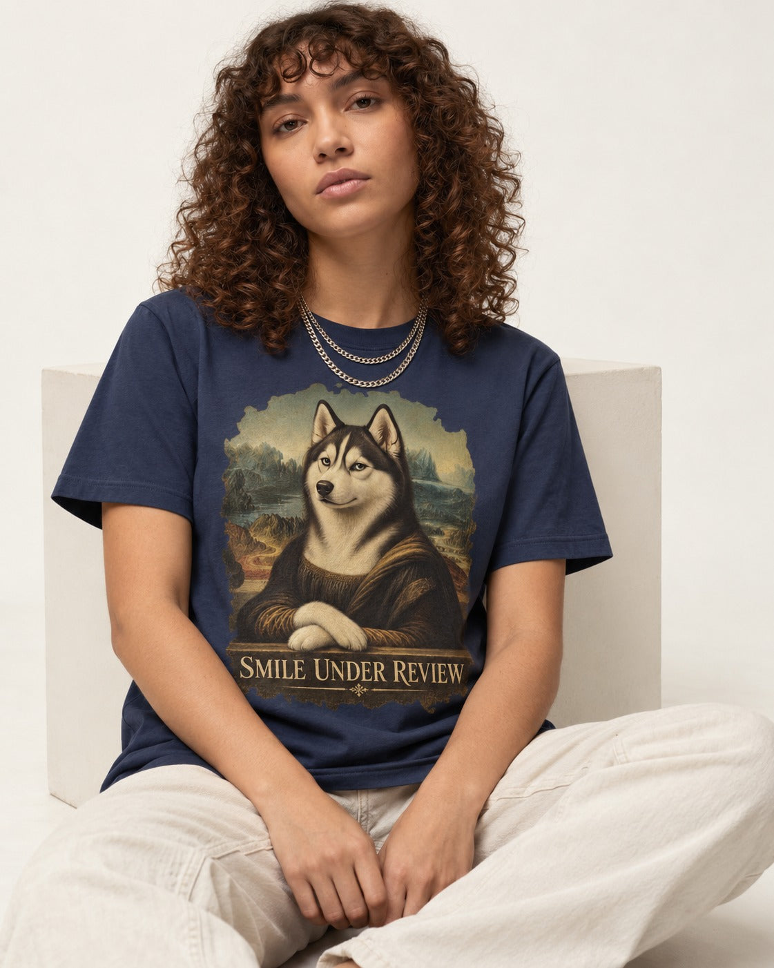 Husky Smile Under Review Renaissance Portrait Graphic T-Shirt in Navy, worn by a seated model