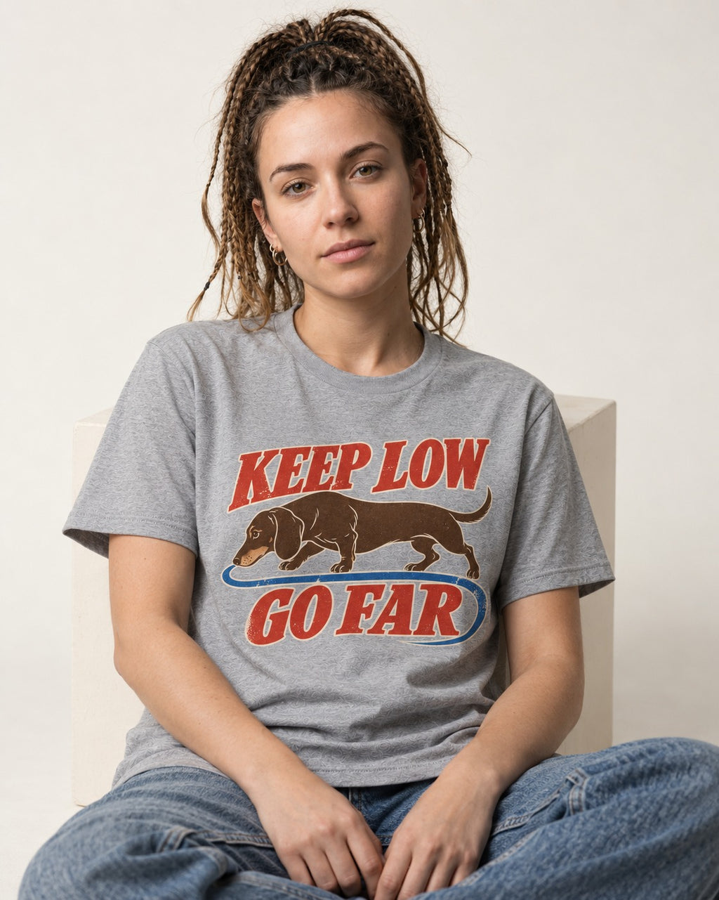 Dachshund Keep Low Go Far T-Shirt in Sport Grey, worn by a seated model