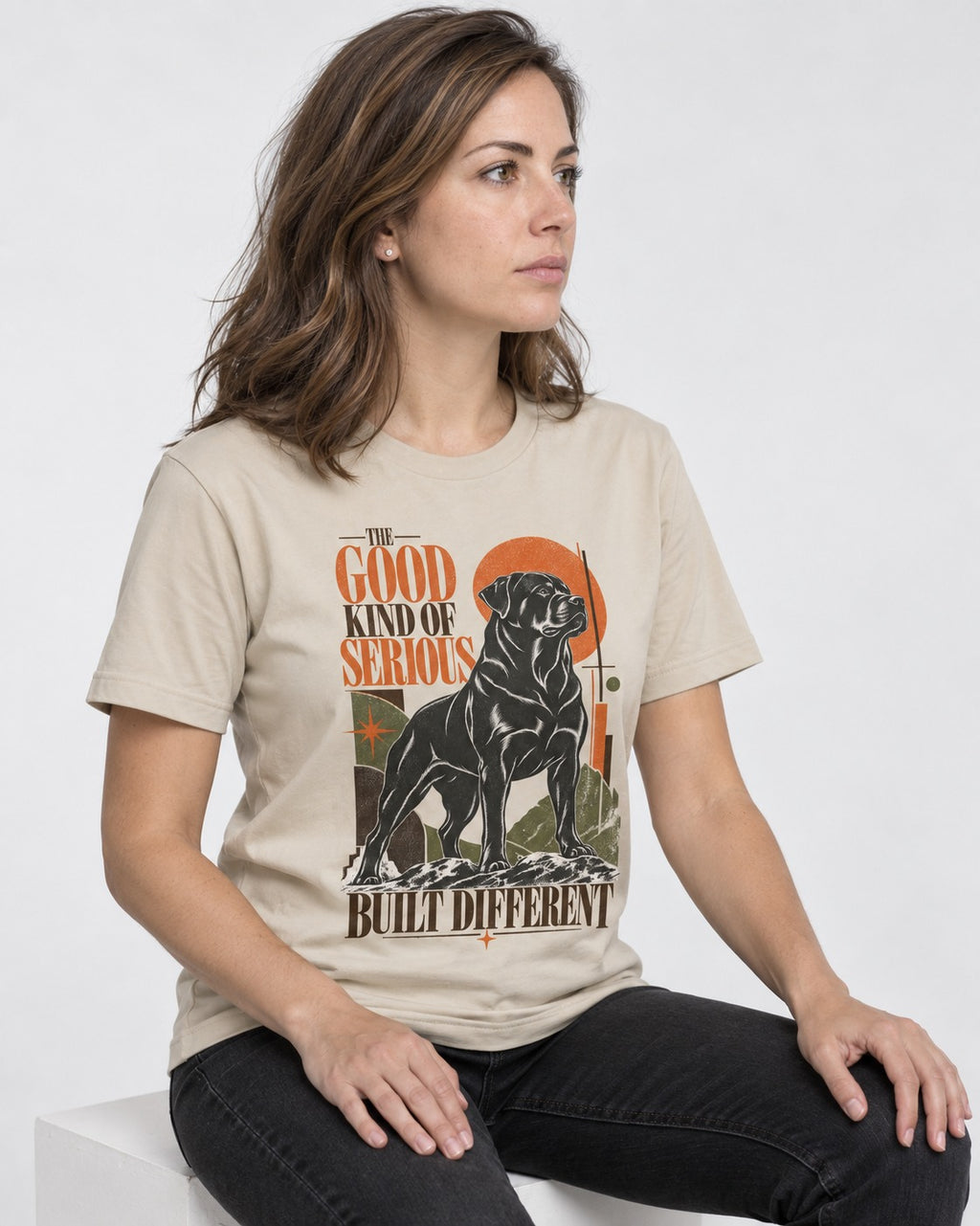 Rottweiler Built Different T-Shirt in Sand, worn by a seated model