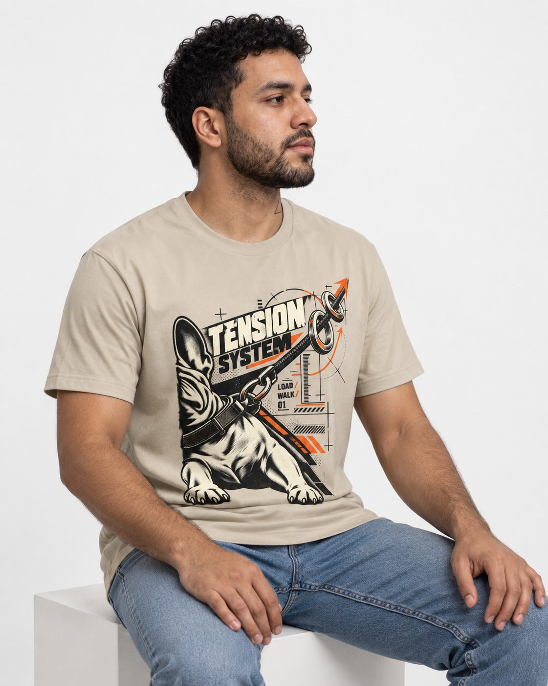 Frenchie Tension System T-Shirt in Sand, worn by a seated model