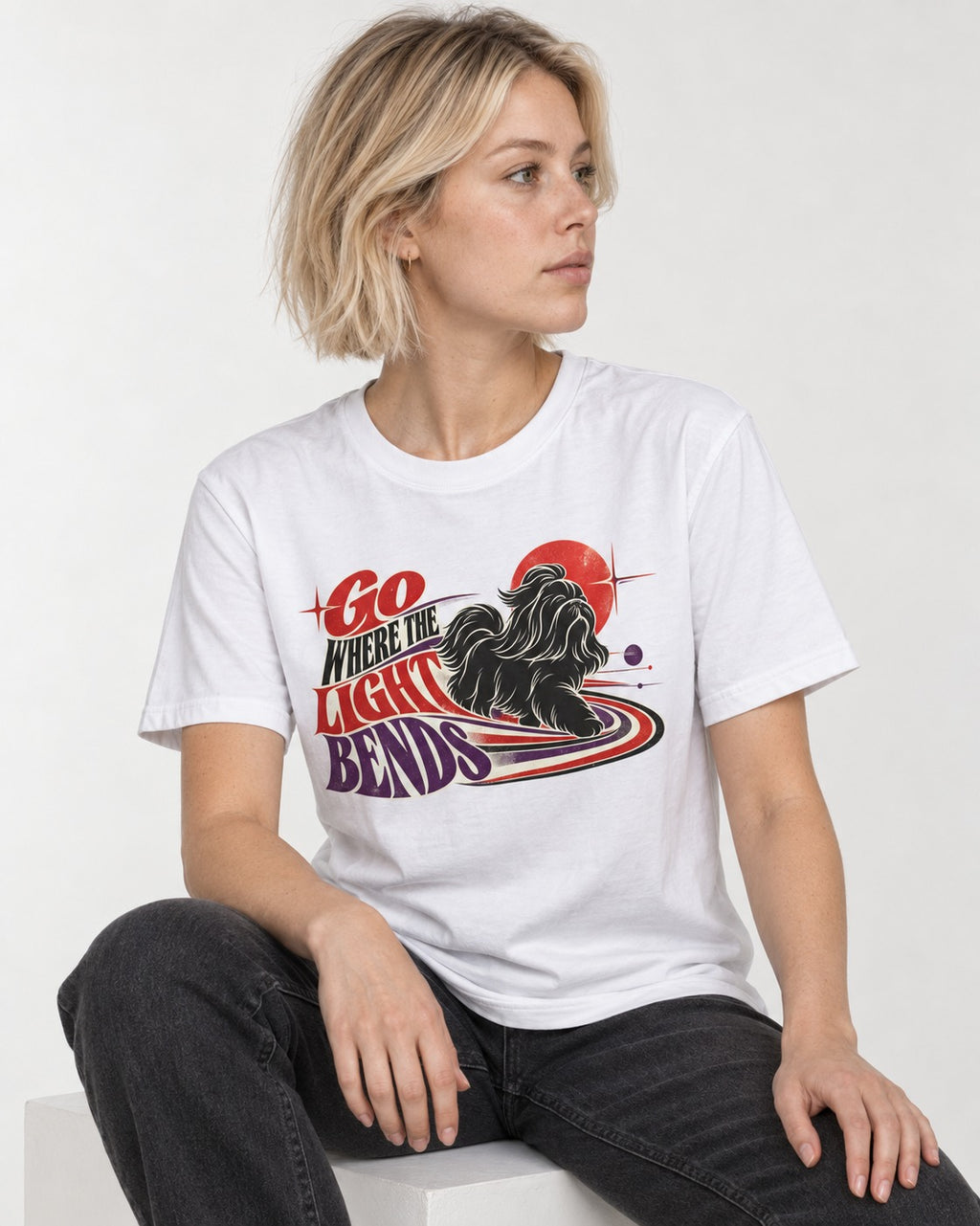 Shih Tzu Go Where the Light Bends Cosmic Orbit Graphic T-Shirt in White, worn by a seated model