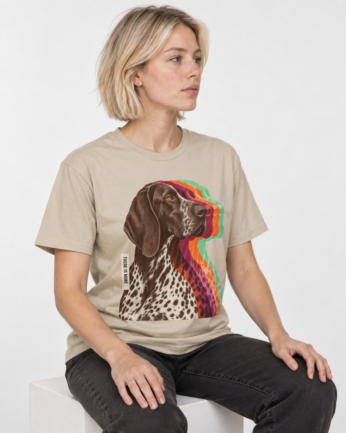 There Is More German Shorthaired Pointer T-Shirt in Sand, worn by a seated model
