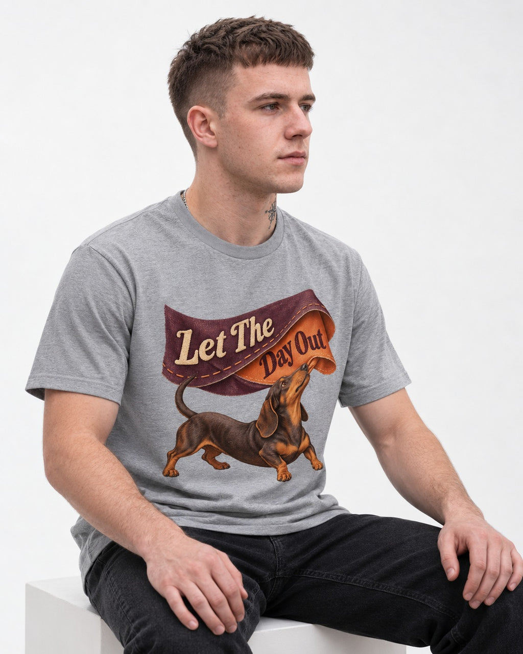 Dachshund Let The Day Out Fabric Banner Graphic T-Shirt in Sport Grey, worn by a seated model
