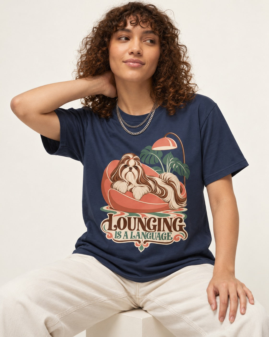Shih Tzu Lounging Is a Language Retro Lounge Graphic T-Shirt in Navy, worn by a seated model