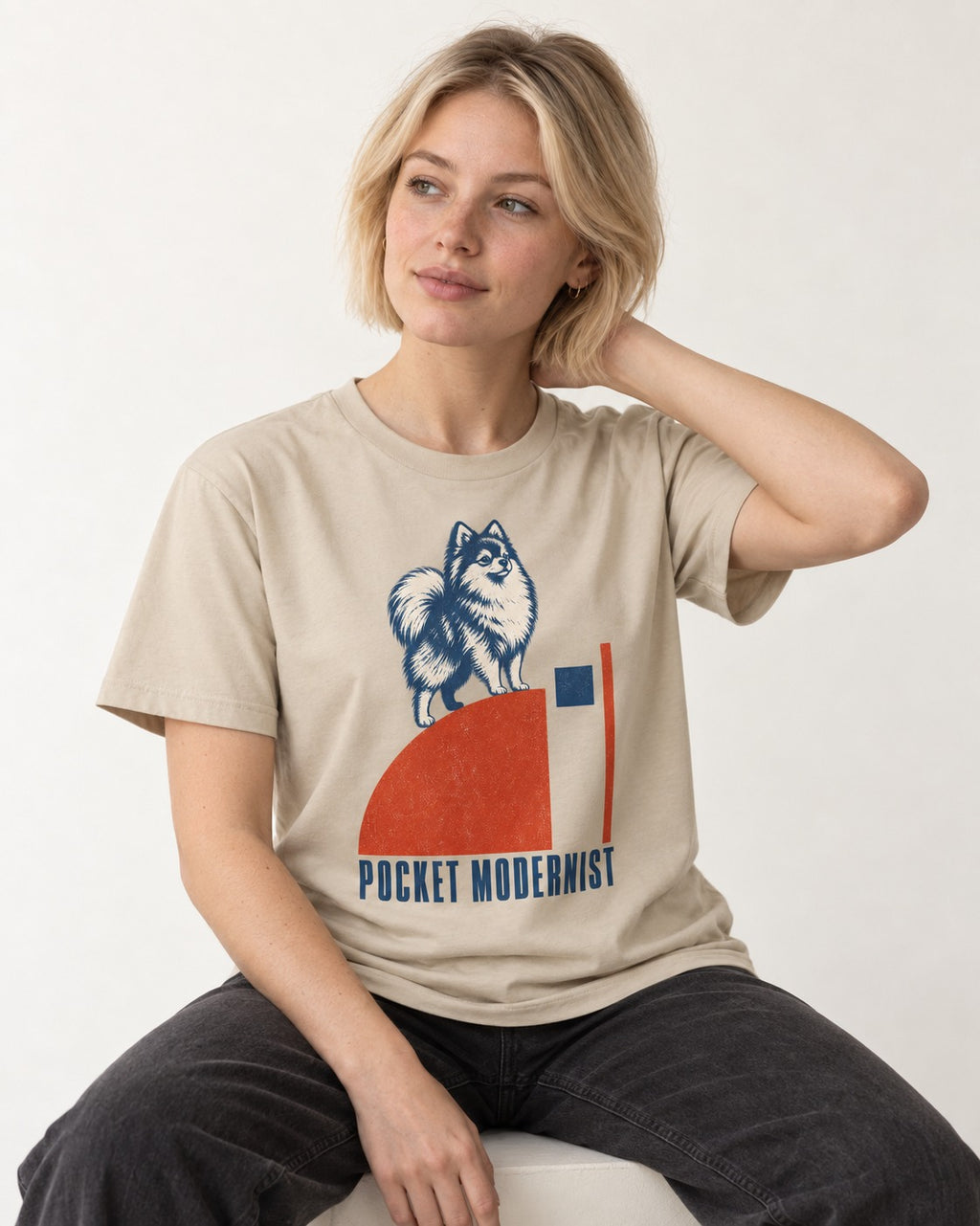 Pocket Modernist Pomeranian T-Shirt in Sand, worn by a seated model