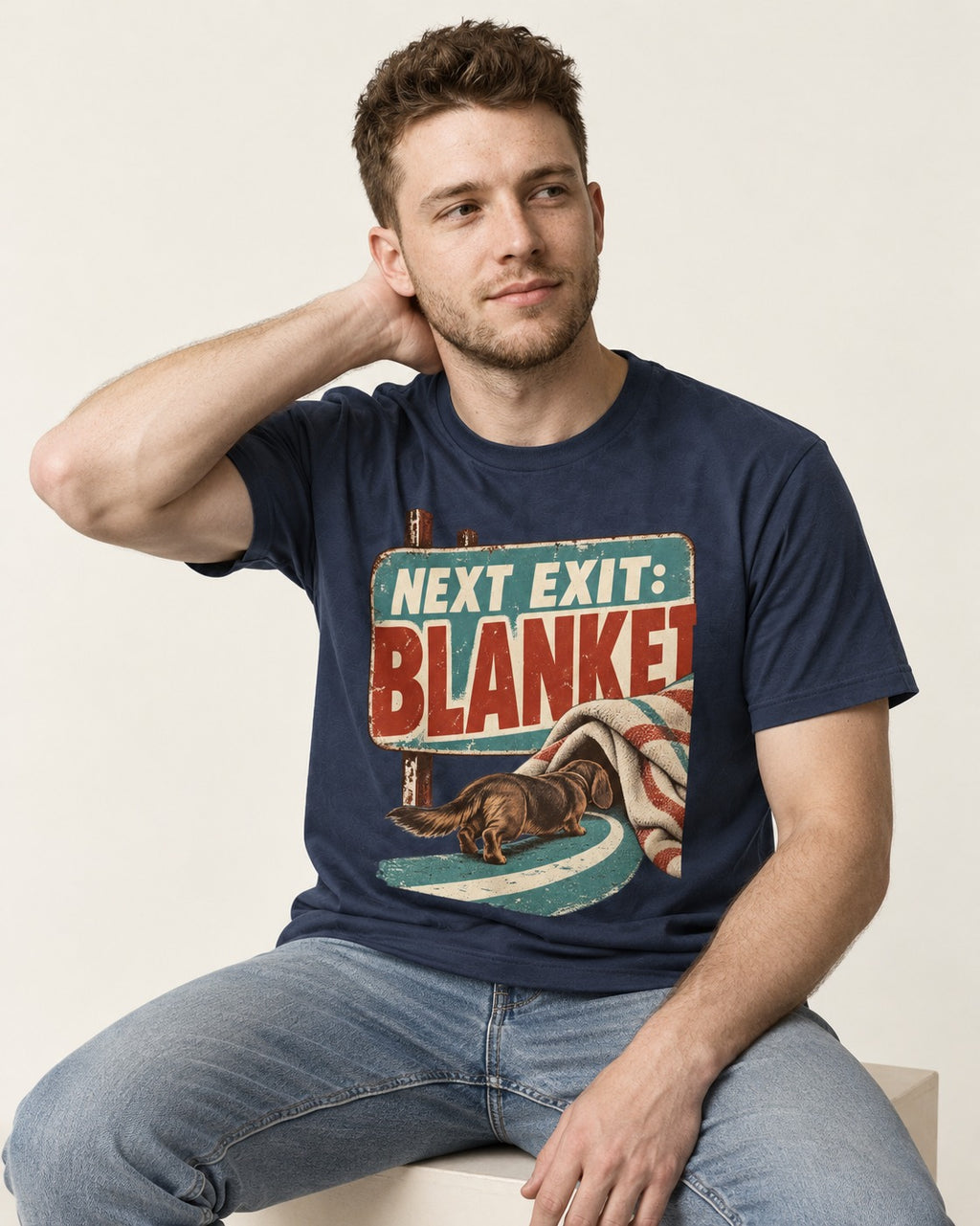 Dachshund Next Exit Blanket Road Sign Graphic T-Shirt in Navy, worn by a seated model