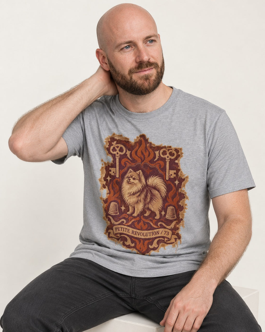 Pomeranian Petite Revolution Ornate Key Emblem Graphic T-Shirt in Sport Grey, worn by a seated model