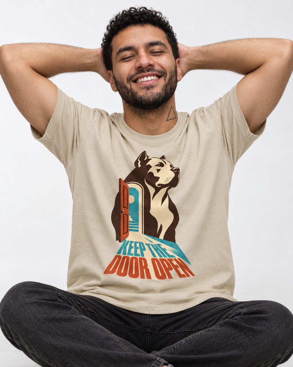 Keep the Door Open Pitbull T-Shirt in Sand, worn by a seated model