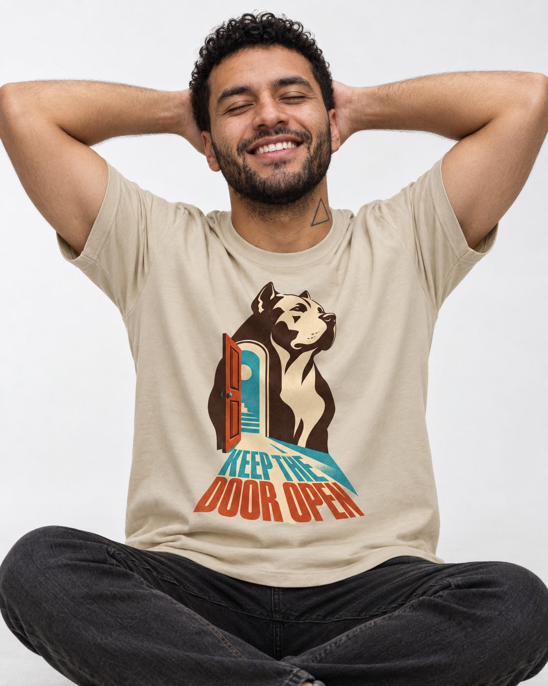 Keep the Door Open Pitbull T-Shirt in Sand, worn by a seated model