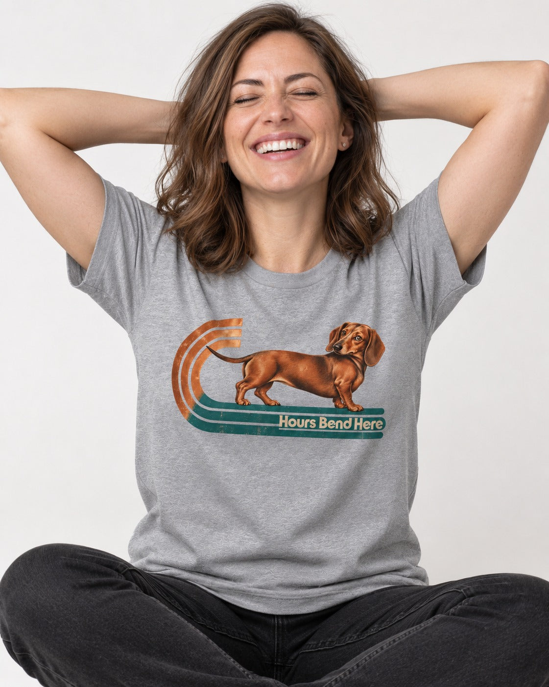 Dachshund Hours Bend Here Retro Track Graphic T-Shirt in Sport Grey, worn by a seated model