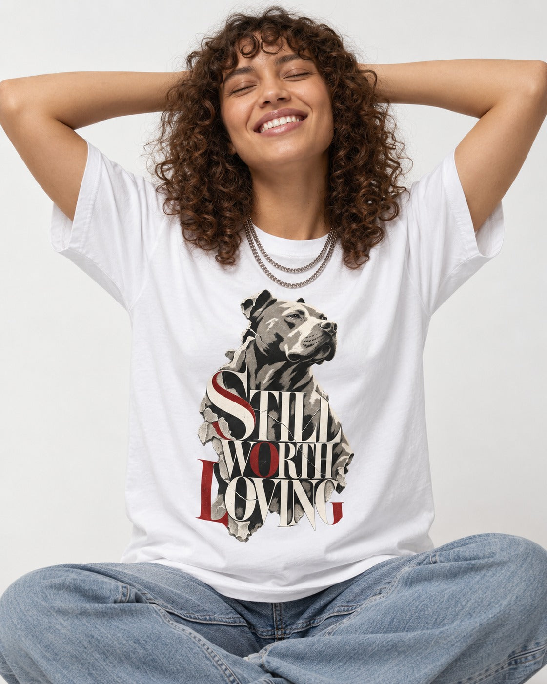 Pitbull Still Worth Loving Torn Poster Portrait Graphic T-Shirt in White, worn by a seated model