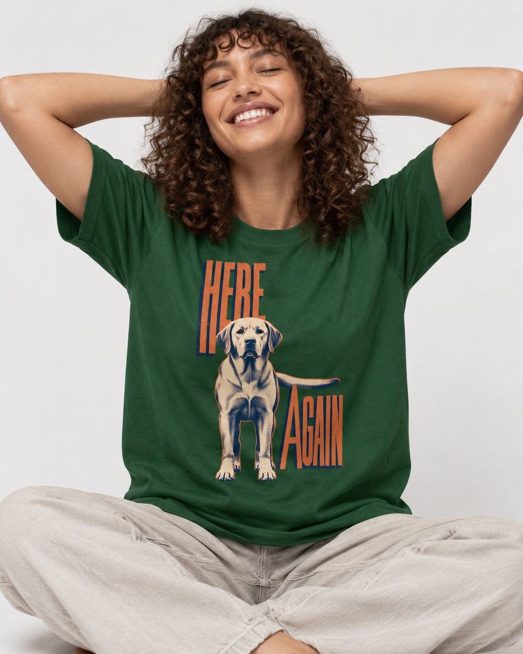 Labrador Retriever Here Again Standing Typography Graphic T-Shirt in Forest Green, worn by a seated model